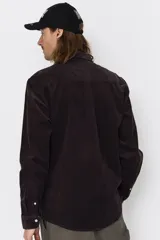 Camisa de pana de algodón manga larga, color negro, con cuello abotonado, cierre frontal con botones y logo bordado en el pecho.