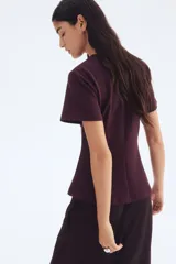 Top de manga corta color borgoña, con cuello redondo y corte entallado que se acampana ligeramente hacia el bajo gracias a las pinzas moldeadoras frontales.