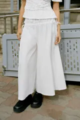 Pantalón culotte de tiro medio, color blanco, con cintura elástica y lazadas laterales ajustables.