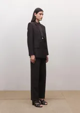 Blazer cruzado de doble botonadura, color marrón oscuro, con solapas de muesca, bolsillos con solapa y hombreras estructuradas.