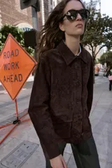 Cazadora de ante color marrón oscuro, con cuello solapa, manga larga y cierre frontal de botones. Incluye dos bolsillos delanteros de plastrón con solapa.