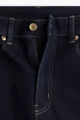 Jean de cinco bolsillos en denim oscuro, con leve elasticidad. Corte ajustado de tiro alto, ceñido desde la cintura hasta las piernas extraajustadas.