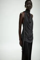 Top halter de viscosa con estampado de lunares, cuello halter, espalda descubierta y detalle de lazadas en el mismo tejido. Cuenta con bajo redondeado y cierre trasero con botones.