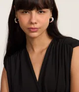 Body femenino de la marca Blue Steel, confeccionado en tejido de poliéster con elastano. Presenta un diseño sin mangas con escote en V cruzado y detalle de hombreras, ofreciendo un ajuste cómodo y elegante.