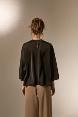 Blusa de satén color negro, con cuello redondo a la base, mangas 3/4 con abertura lateral y diseño holgado.