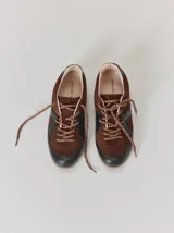 Championes de cuero con diseño combinado en color marrón y negro. Presentan una estructura de gamuza marrón con refuerzos de cuero liso negro en la puntera y laterales, cordones bicolores y suela de goma.