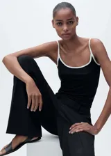Musculosa negra con tirantes finos blancos y cuello redondo con ribete blanco. Diseño ajustado al cuerpo.