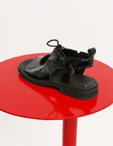 Sandalias negras de cuero charol con cordones y tira trasera.