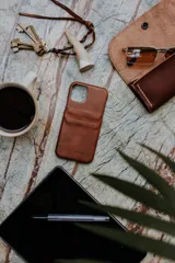 Funda para celular de cuero marrón, con ranuras posteriores para tarjetas y el logo grabado de la marca Sierra Mora.
