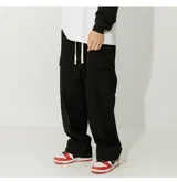 Pantalón cargo negro de pana, de corte ancho y holgado, con cintura ajustable mediante cordón blanco y cuatro bolsillos funcionales (dos laterales y dos cargo).