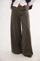 Pantalón de tiro medio confeccionado en tencel, con diseño de pierna ancha y cortes curvos que aportan movimiento. Presenta cierre frontal con botón, bolsillos delanteros y bolsillos plaque en la parte trasera.