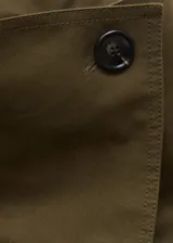 Abrigo tipo trench de diseño oversize y corte recto, color verde militar. Presenta cuello de solapa ancha, cierre frontal de doble botonadura, cinturón desmontable con hebilla y bolsillos laterales. Incluye trabillas en los puños y forro interior.