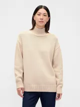 Buzo de algodón color beige con cuello polera, manga larga y diseño holgado con puños y dobladillo en rib.