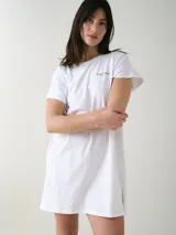 Camisón blanco de algodón, de corte holgado, manga corta y largo por encima de las rodillas. Presenta una pequeña estampa localizada en el pecho y aberturas en los laterales.