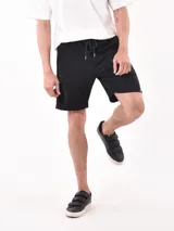 Bermuda negra con textura acanalada horizontal, corte a la rodilla y cintura con cordón ajustable.