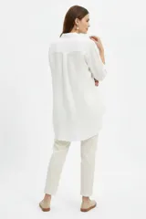 Camisa blanca de viscosa de corte oversize, con cuello camisero, cierre frontal de botones y bolsillo ojal en el pecho.