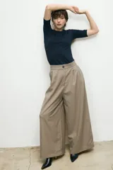 Pantalón sastre de corte wide leg y tiro alto, en color beige. Presenta pinzas frontales, cierre con botón y bolsillos laterales.
