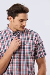 Camisa de manga corta con estampado de cuadros en tonos azules, rojos y blancos, cuello con botones y bolsillo ojal en el pecho con logo bordado.