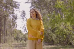 Buzo amarillo mostaza de tejido de punto acanalado, con mangas largas acampanadas y puños en color rosa claro.