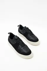 Zapatillas urbanas negras con detalles en gamuza y suela blanca.