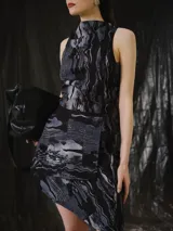 Falda corta de silueta estructurada, confeccionada en tejido estampado en tonos negro, gris y azul. Cuenta con cintura regulable, panel frontal superpuesto y terminación asimétrica.