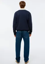 Pantalón de jean azul oscuro, de corte recto y tiro mediano, con bolsillos laterales y traseros, y costuras en contraste.