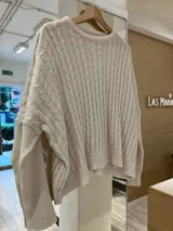 Sweater color beige con cuello redondo y diseño de trenzas en relieve.