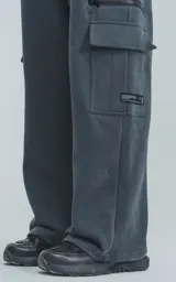 Pantalón de jogging de frisa color gris melange oscuro, con cintura y puños elásticos. Posee dos bolsillos laterales, un bolsillo trasero y un bolsillo lateral adicional con cierre.