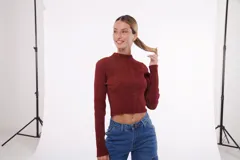 Buzo cropped de punto color ladrillo con brillo dorado, cuello alto y mangas largas.