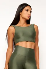 Top deportivo color terracota, de corte crop y manga sisa, con cuello redondo y espalda escotada. Presenta textura acanalada y acabado brillante.