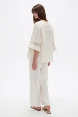 Blusa de algodón blanca de corte holgado, con cuello redondo y detalles de broderie en las mangas y costuras frontales.