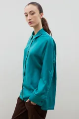 Camisa de corte holgado y diseño clásico, confeccionada en tela satinada con un sutil estampado floral tono sobre tono. Presenta cuello camisero, cierre frontal con botones y mangas largas con puños rectos.