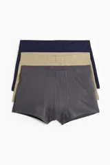 Pack de tres calzoncillos tipo bóxer de algodón, con costuras planas, elástico revestido en la cintura y refuerzo frontal. Los colores son gris oscuro, beige y azul marino.