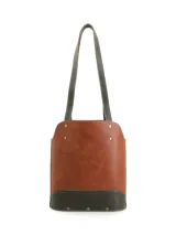 Matera de cuero con diseño bicolor en tonos marrón y verde oliva, con correas largas para hombro y detalles de remaches metálicos. Incluye logo de la marca grabado en el frente.