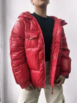 Campera puffer roja con capucha, bolsillos frontales y cordón ajustable en el ruedo.