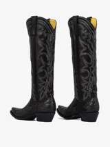 Bota texana de cuero color negro, caña alta, con punta cuadrada y tacón medio. Presenta bordados decorativos en hilo gris claro en la caña y el empeine.