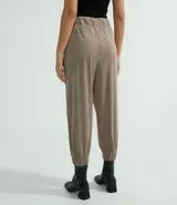 Pantalón estilo jogger de suedine, con cintura elástica y cordón ajustable, puños elásticos en los tobillos, bolsillos laterales y detalles perforados en los laterales y bolsillos.