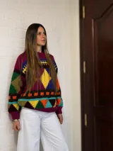 Sweater de lana merino con estampado Fair Isle en tonos azul marino, beige, naranja, verde oliva y bordó. Tiene cuello redondo y mangas largas.