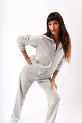 Conjunto de dos piezas confeccionado en tela plush, compuesto por una campera con cierre frontal y cuello alto, y un pantalón de corte recto. Presenta un diseño minimalista y cómodo en color gris claro.