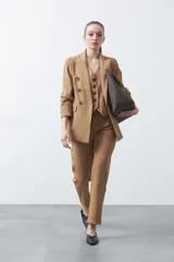 Blazer sastrero color camel de doble botonadura con botones marrones, cuello solapa y mangas largas.