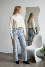 Jean de corte recto y tiro medio, confeccionado en denim celeste con estampado floral en tonos claros. Presenta cierre frontal con botón y bolsillos laterales y traseros.