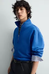 Sudadera de algodón azul con cuello alto y cierre frontal de cremallera de un cuarto. Presenta un corte regular y puños y bajo en rib.