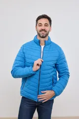 Campera capitoneada liviana de color azul con cuello alto e interior a contratono. Presenta un diseño con costuras horizontales, cierre frontal completo y dos bolsillos laterales con cremallera.