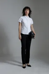 Camisa blanca de corte clásico, con cuello camisero, mangas cortas y cierre frontal con botones.