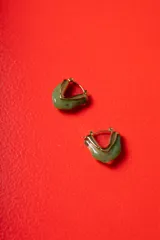 Aros tipo argolla de diseño escultórico y asimétrico, combinando metal dorado con resina en tono verde marmolado.