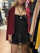 Vestido corto de lentejuelas plateadas y negras, con diseño cut-out en la cintura, escote halter con argolla central y falda con volado en el ruedo.