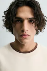 Sudadera de tejido con algodón, color beige claro, de corte relajado (relaxed fit) y cuello redondo. Presenta un parche bordado en el pecho con el logo de Ford y el texto "Genuine Parts" en azul marino.