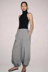 Pantalón de tiro medio con pierna ancha y cintura elástica, confeccionado en mezcla de viscosa con diseño de rayas verticales en tonos mostaza y marrón.