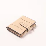 Billetera color beige con detalles de costuras decorativas en negro, cierre de solapa con botón a presión y un compartimento con cierre de cremallera.