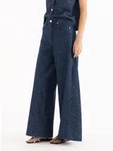 Pantalón wide leg de tiro medio-alto, confeccionado en denim de algodón azul con patrón de cuadros. Cuenta con recortes laterales que aportan volumen y caída fluida, además de bolsillos delanteros y traseros.